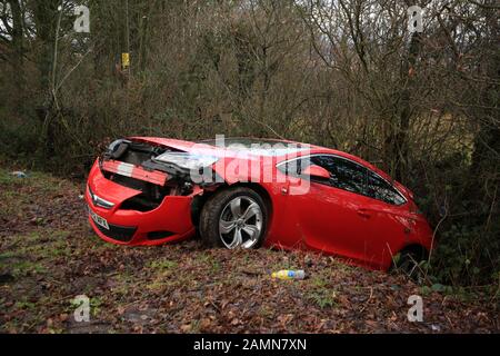 Une voiture rouge abandonné dans un fossé dans la campagne britannique. Banque D'Images