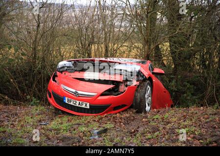 Une voiture rouge abandonné dans un fossé dans la campagne britannique. Banque D'Images