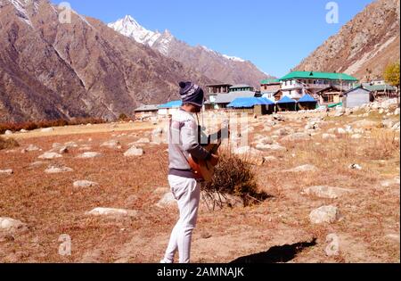 Musicien amateur solo jouant de la guitare seul dans le silence de la vallée de montagne de l'Himalaya et du son des cordes de guitare. La musique d'été Inspire Banque D'Images