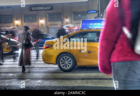 Exposition longue d'une rue à Manhattan la nuit pendant la période de Noël. Mouvement rapide des personnes traversant une route. Focalisation sélective sur les taxis jaunes. Banque D'Images