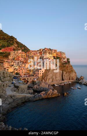 Les maisons colorées peintes et le port du village de pêcheurs haut de la falaise de Manarola au coucher du soleil, Parc national des Cinque Terre, Ligurie Italie eu Banque D'Images
