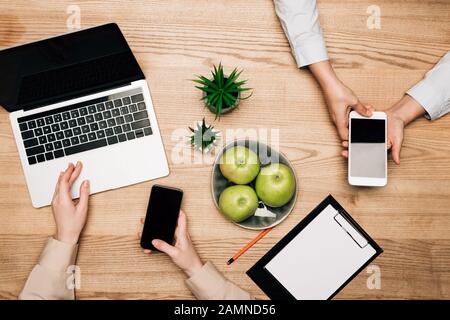 Vue de dessus des professionnels utilisant des smartphones et un ordinateur portable par pommes et presse-papiers sur la table Banque D'Images