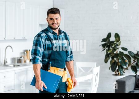 homme de travail heureux barbu debout et tenant le presse-papiers Banque D'Images