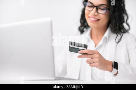 Femme d'affaires hispanique souriante utilisant une carte de crédit au bureau Banque D'Images