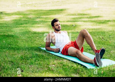 beau sportif allongé sur un homme de fitness dans le parc Banque D'Images