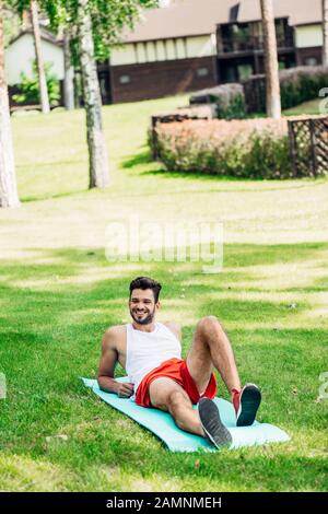 un sportif heureux allongé sur un homme de fitness dans le parc Banque D'Images