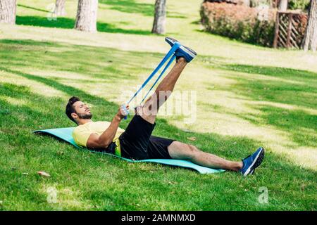 homme barbu faisant de l'exercice avec des sangles de suspension tout en reposant sur un tapis de fitness Banque D'Images