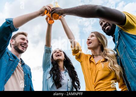 vue de dessous des bonnes bouteilles de clinking multiculturelles pour hommes et femmes avec bière Banque D'Images