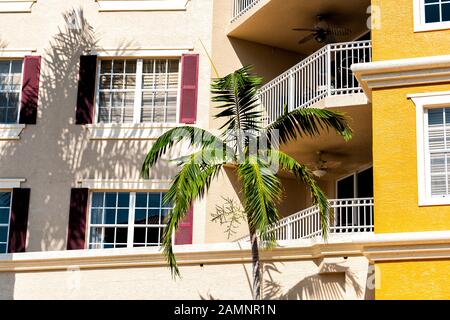 Florida condominium coloré jaune multicolore bâtiments façade extérieure avec fenêtres, palmiers, immobilier architecture espagnole Banque D'Images