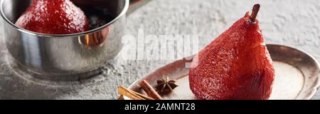 délicieuse poire en vin dans le stewpan et sur la plaque d'argent avec cannelle et anis sur surface en béton gris, photo panoramique Banque D'Images