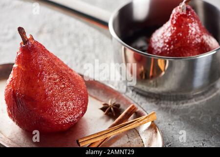 foyer sélectif de la délicieuse poire dans le vin dans le stewpan et sur la plaque d'argent avec cannelle et anis sur la surface de béton gris Banque D'Images