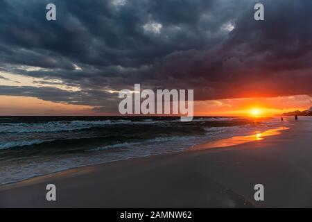 Orange rouge, coucher de soleil spectaculaire à Santa Rosa Beach, Floride avec côte de côte dans le panhandle avec l'océan golfe mexique vagues pendant la tempête d'ouragan Banque D'Images