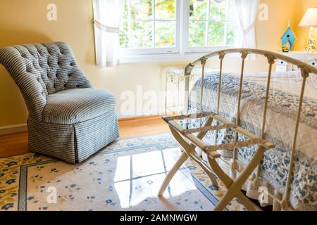 Chambre ancienne rétro jaune clair avec chaise confortable et décorations de lit dans la maison Banque D'Images