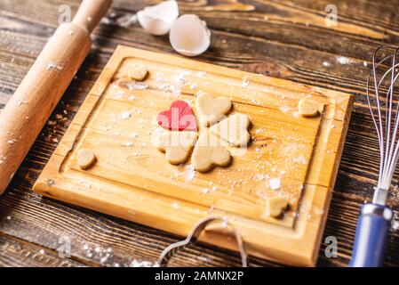 Cuisson de cookies à partir de la pâte en forme de coeur sur fond en bois sombre. Cuisson pour la Saint-Valentin et une date romantique Banque D'Images