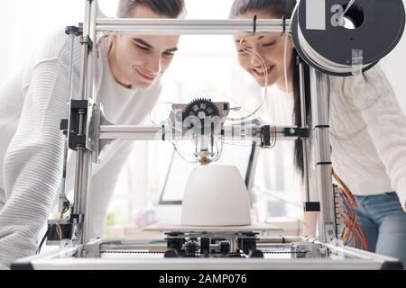 Les étudiants en ingénierie qui utilisent une imprimante innovante en trois dimensions dans le laboratoire universitaire impriment un prototype ensemble, une créativité et un concept d'éducation Banque D'Images
