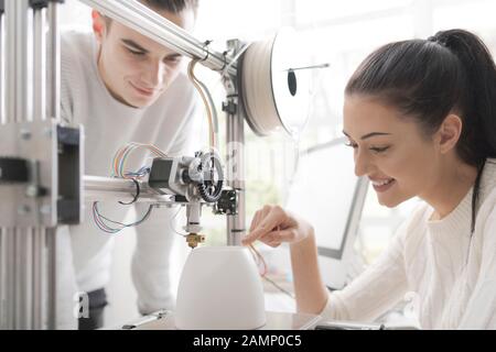 Les étudiants en ingénierie qui utilisent une imprimante innovante en trois dimensions dans le laboratoire universitaire impriment un prototype ensemble, une créativité et un concept d'éducation Banque D'Images