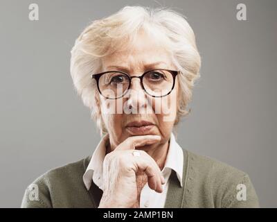 Pensive senior femme pensant à la main sur le menton, elle est triste et inquiète Banque D'Images