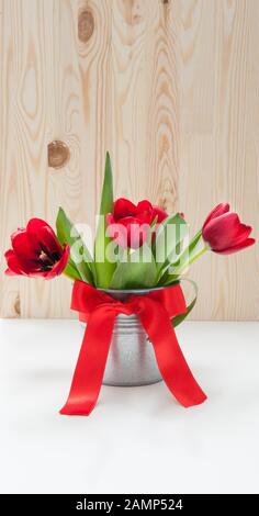Bouquet de tulipes dans un seau en fer avec un noeud rouge Banque D'Images