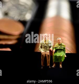 Miniatures, couple retraité assis sur l'argent,cash,pièces,concept Banque D'Images