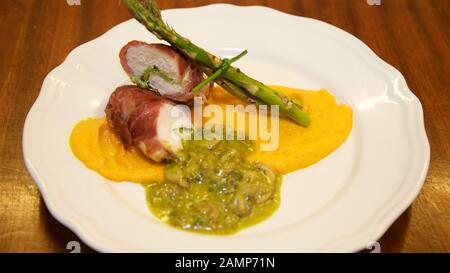 Un restaurant plat principal plat de poulet enveloppé dans du jambon de parme servi avec des asperges, champignons et purée de patate douce. Banque D'Images