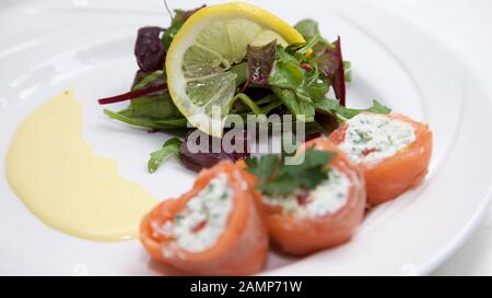 Un plat de départ de restaurant de saumon fumé roulé et de fromage à la crème. Banque D'Images