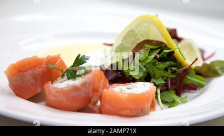 Un plat de départ de restaurant de saumon fumé roulé et de fromage à la crème. Banque D'Images