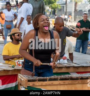 Le Cap, Afrique Du Sud. Musiciens de rue s'amuser avec les touristes sur le secteur riverain du centre de Cape Town. La femme interagit Banque D'Images