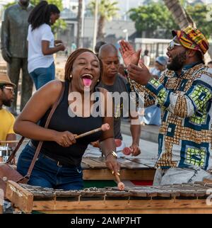 Le Cap, Afrique Du Sud. Musiciens de rue s'amuser avec les touristes sur le secteur riverain du centre de Cape Town. La femme interagit Banque D'Images