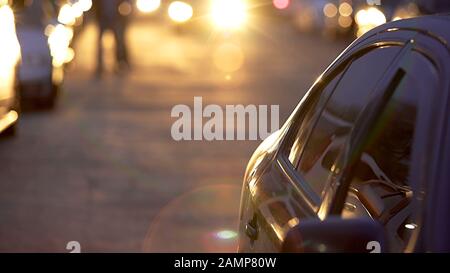 Automobile roulant lentement sur le parking pendant le coucher de soleil magique, stationnement automatique Banque D'Images