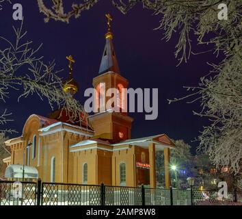 La construction de l'église orthodoxe la nuit entourée d'arbres dans la neige. Banque D'Images