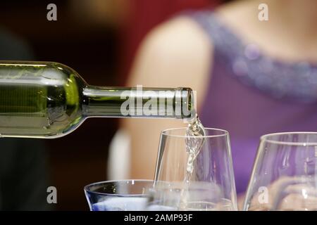 Gros plan de vin blanc versé à une vineglass. Banque D'Images