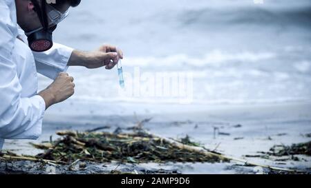 Scientifique prenant un échantillon d'eau sur le rivage, problèmes de santé causés par la pollution Banque D'Images