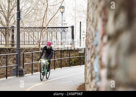 Un cycliste en collants noirs et en casque rose passe dans un coin. Banque D'Images