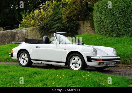 Années 80 Blanc Porsche 911 Cabriolet avec intérieur en cuir noir et jantes en alliage de couleur Fuchs garé sur un village anglais lane Banque D'Images