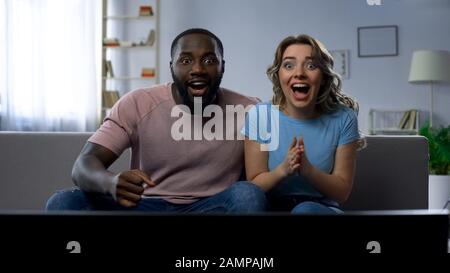 Couple regardant le match de sport sur la maison de télévision, célébrant la victoire, jeu réussi Banque D'Images