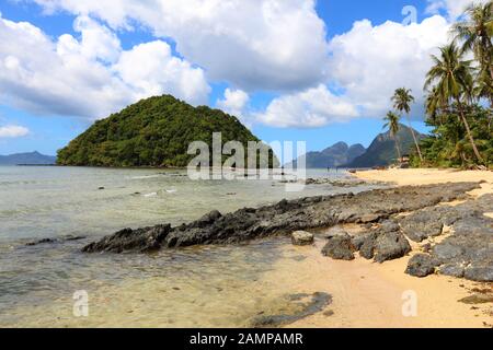 Se penchant palmiers de Las Cabanas beach à El Nido, l'île de Palawan, Philippines. Banque D'Images