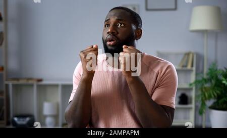 Un homme enchanté qui regarde un match de football à la télévision à la maison, soutient l'équipe nationale Banque D'Images