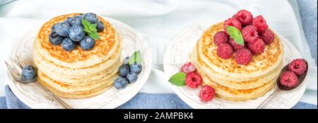 Deux piles de crêpes décorées de framboises mûres et de bleuets sur fond de serviette bleu-blanc Banque D'Images