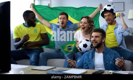 Les amis brésiliens enthousiastes applaudisent à l'équipe nationale, célébrant l'objectif gagnant Banque D'Images