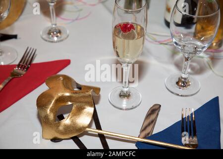 Masque de balle en mascarade doré sur une table de dîner. Carnaval Venetian Eye Mask, accessoire de robe fantaisie, boule de costume de fête de Carnaval. Banque D'Images