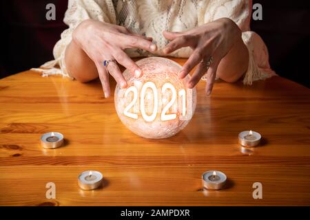 Fortune Teller avec Crystal ball sur table avec bougies et année 2021 en boule Banque D'Images