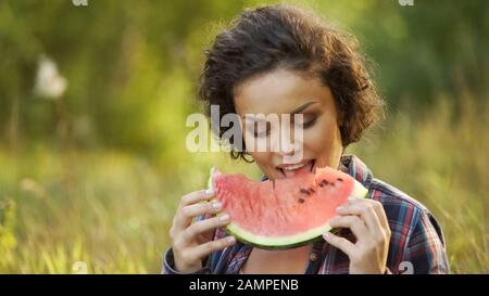 Belle dame qui mange du pastèque frais et juteux assis dans le parc, nourriture saine Banque D'Images