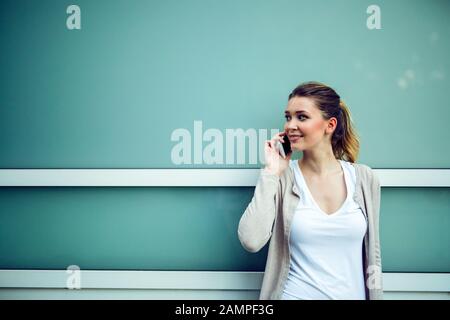 Femme réussie ou un entrepreneur talking on cellphone en marchant à l'extérieur. Banque D'Images