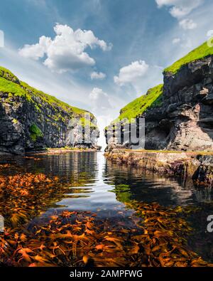 Belle vue sur quai ou le port avec de l'eau claire et l'algue rouge dans Eysuroy mais confortables et disposent village, Île, Îles Féroé, Danemark. Photographie de paysage Banque D'Images