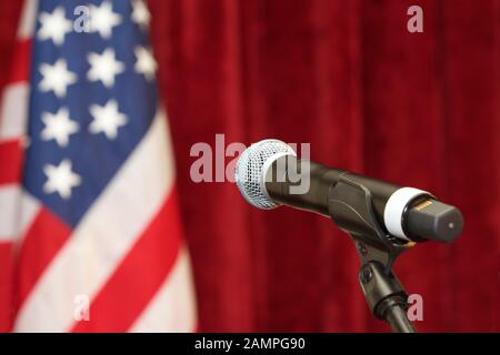 Sur le stand de microphone sans fil avec le drapeau américain en arrière-plan. Banque D'Images
