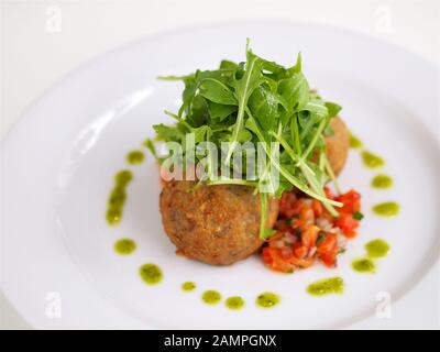 Fromage de chèvre frit servi avec des feuilles de roquette et salsa de tomates. Banque D'Images