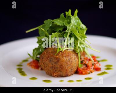 Fromage de chèvre frit servi avec des feuilles de roquette et salsa de tomates. Banque D'Images