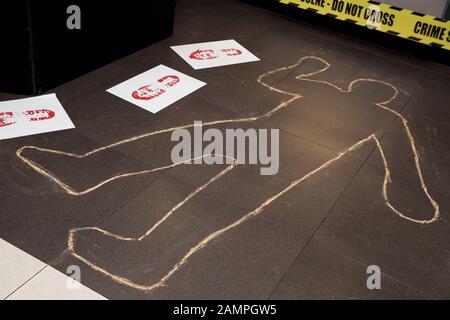 Scène de crime fictive avec ruban jaune cordon de police et craie contours du corps. Banque D'Images