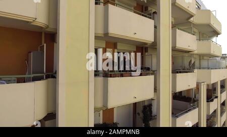 Homme avec une tasse de café debout sur un balcon résidentiel complexe, en appréciant le matin Banque D'Images