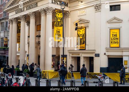 Les personnes qui marchent devant le Lyceum Theatre London couvert de jaune Affiches présentant le spectacle musical Lion King à Covent Garden Londres en janvier 2020 Banque D'Images